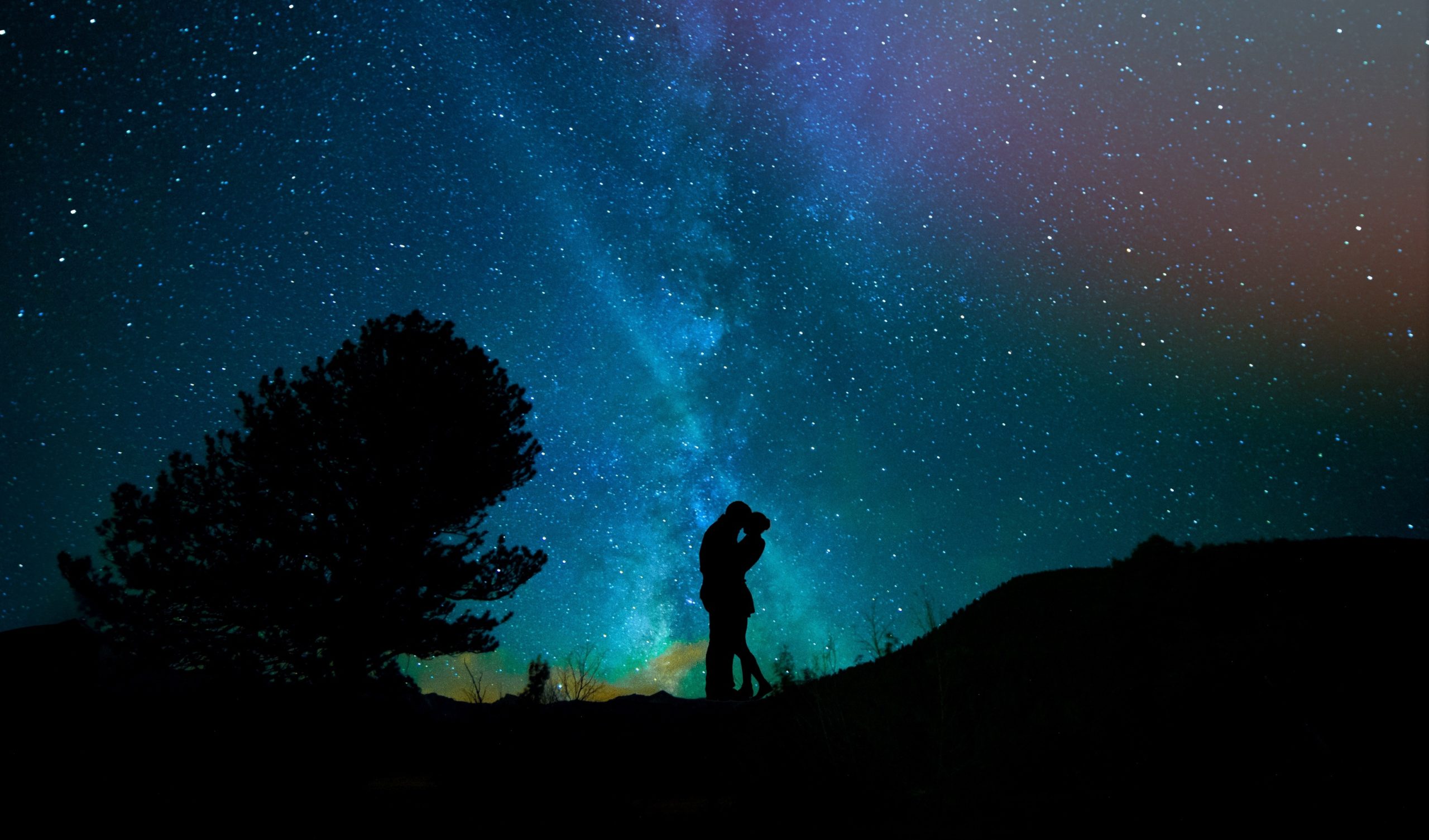 星空の下で抱き合いキスをする男女